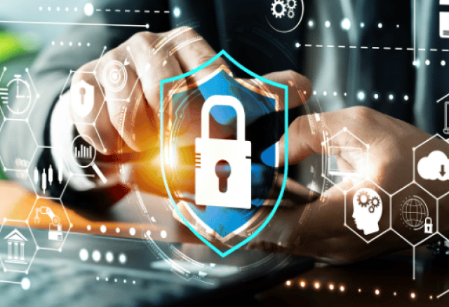 A person working on a laptop surrounded by digital cybersecurity icons, including a central glowing shield with a padlock.